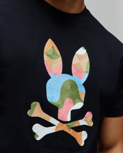Mens Ara Graphic Tee in black jersey knit, featuring a large, central embroidered Psycho Bunny skull and crossbones logo in a multi-color geometric pattern of blue, green, pink, and tan.