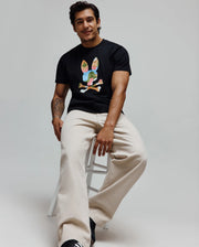 Mens Ara Graphic Tee, a black classic fit jersey t-shirt featuring a large, colorful abstract Psycho Bunny skull and crossbones graphic print on the chest.