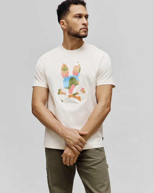 Cream Mens Ara Graphic Tee, classic fit jersey t-shirt featuring a large, geometric multi-color Psycho Bunny skull and crossbones graphic on the chest, with a small brand tag on the hem.