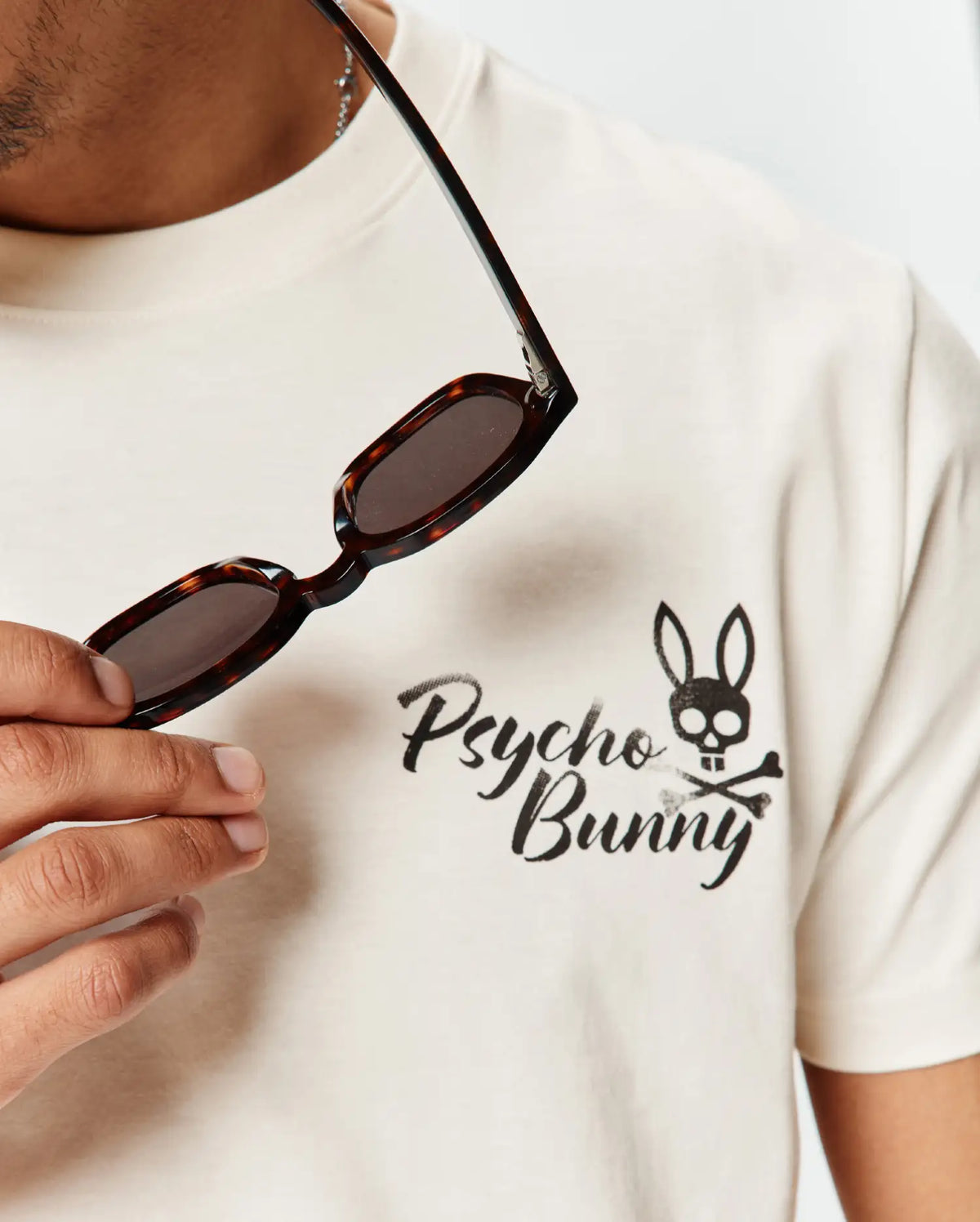 Mens Colin Back Graphic Tee in cream, soft jersey knit, with a front chest graphic: black brushstroke Psycho Bunny text and bunny skull and crossbones logo. (3)