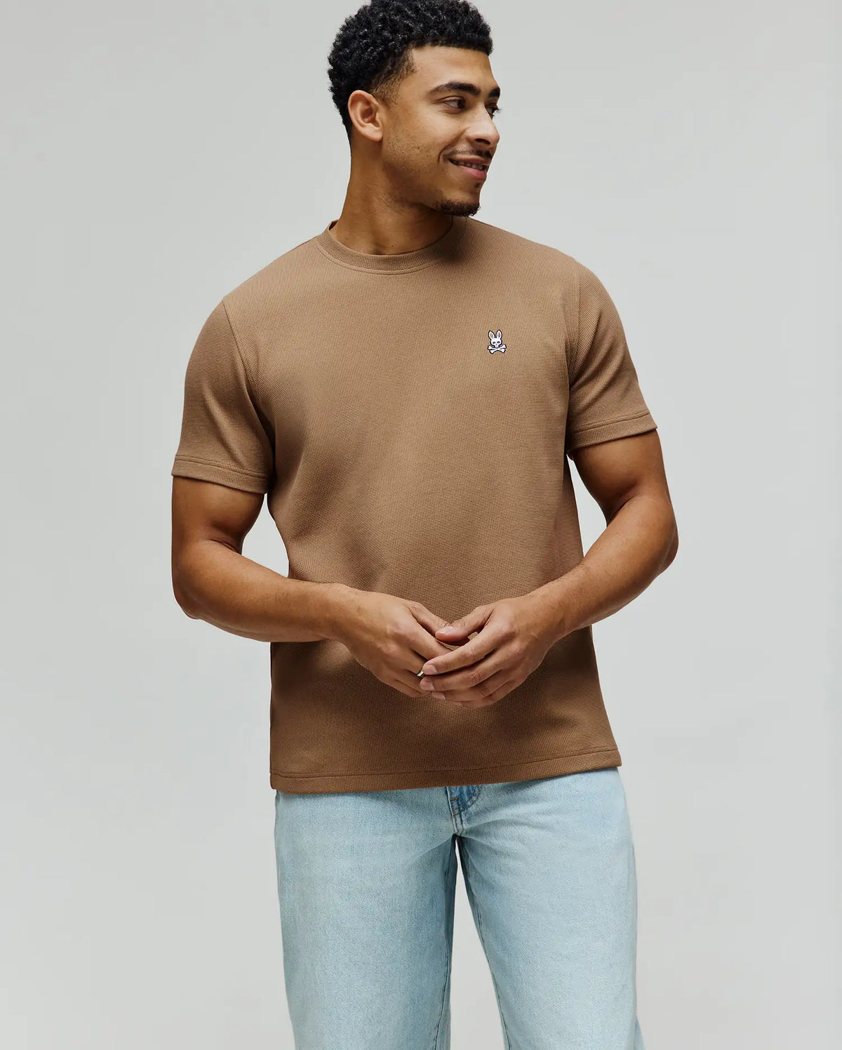 Brown Mens Maxton Waffle Tee, a classic fit waffle knit shirt with a small embroidered white, black, and blue Psycho Bunny skull logo on the left chest.