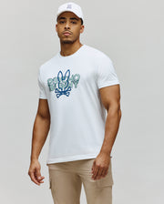 White Mens Herman Graphic Tee, a classic fit jersey t-shirt with a large, distressed blue and green Psycho Bunny text and iconic bunny skull logo graphic on the chest.