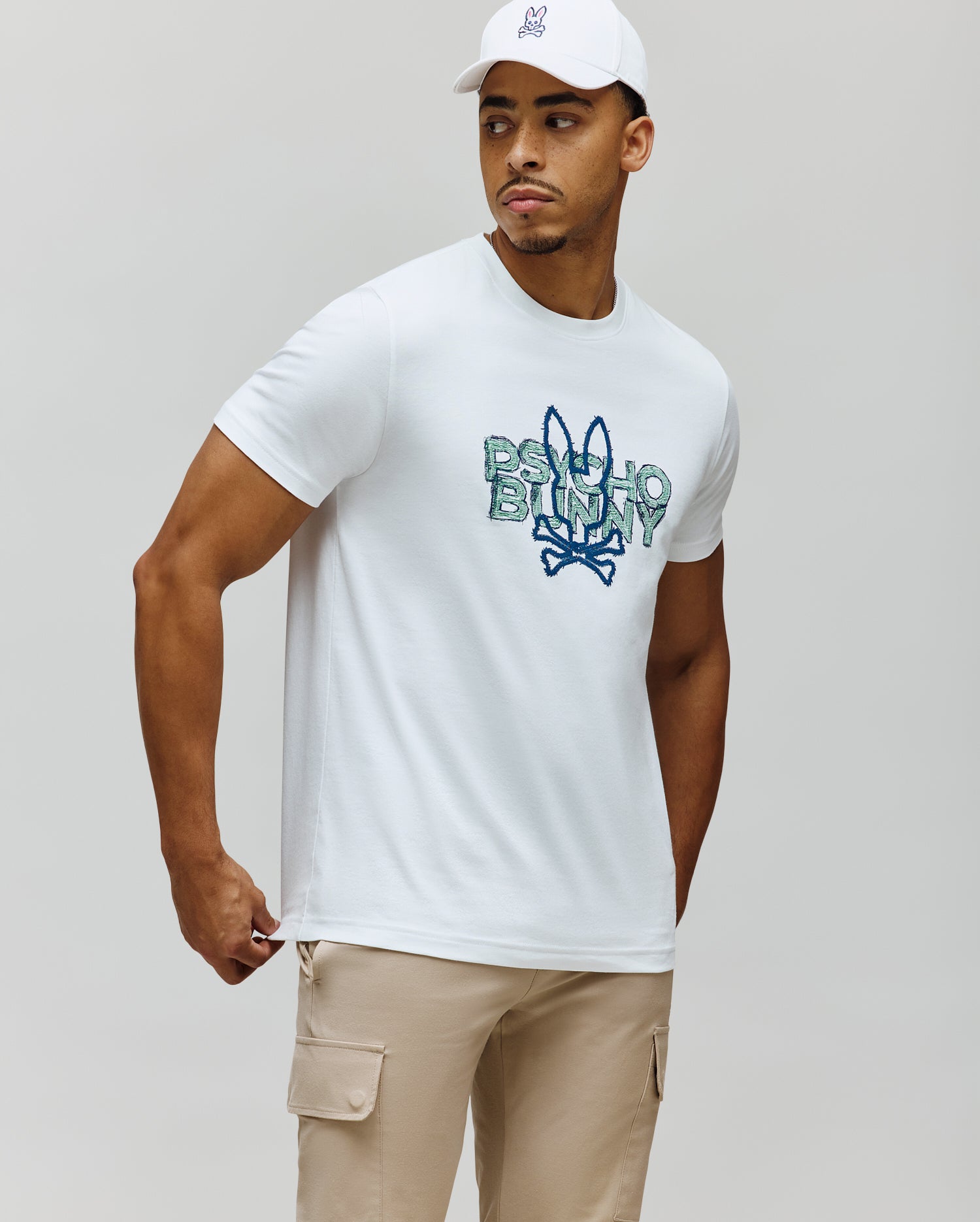 Mens Herman Graphic Tee, white classic fit jersey knit with a large distressed blue and green Psycho Bunny text and skull logo graphic on the chest.