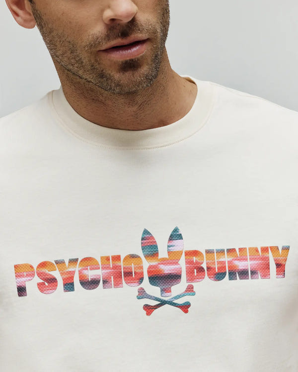 Cream Mens Raphael Wordmark Tee with a large, central chest graphic featuring the Psycho Bunny wordmark and bunny skull logo in a vibrant, multi-color striped pattern on smooth jersey fabric.
