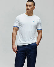 Mens Clark Performance Tee, white classic fit smooth jersey knit t-shirt featuring a small blue embroidered Psycho Bunny skull logo on the left chest and blue striped ribbed cuffs.