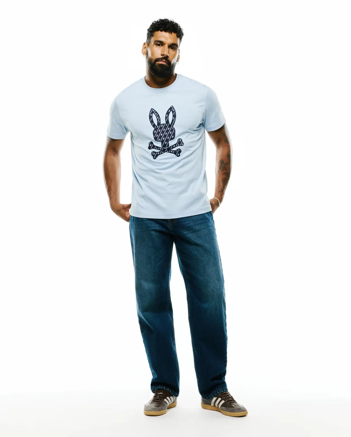 Mens Jaden Appliqué Graphic Tee, a light blue classic fit jersey t-shirt featuring a large central navy and white patterned Psycho Bunny skull and crossbones logo. (5)
