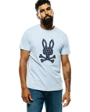 Mens Jaden Appliqué Graphic Tee, a light blue classic fit jersey t-shirt with a large central dark blue and white Psycho Bunny skull logo appliqué, featuring a repeating mini-logo pattern. (2)