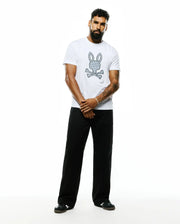 Mens Jaden Appliqué Graphic Tee, a white classic fit soft jersey t-shirt featuring a large center chest Psycho Bunny skull logo with a repeating bunny pattern and crossed bones. (5)