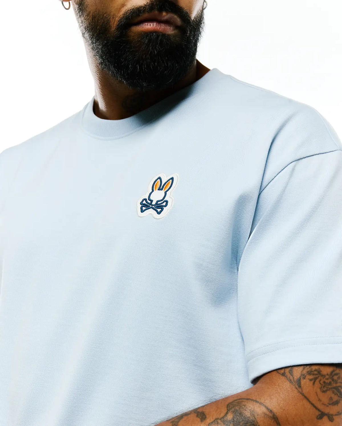 Mens Jaydon Pima Cotton Oversized-Fit Tee in light blue jersey knit, featuring a small embroidered white, orange, and dark blue Psycho Bunny skull logo on the left chest. (2)