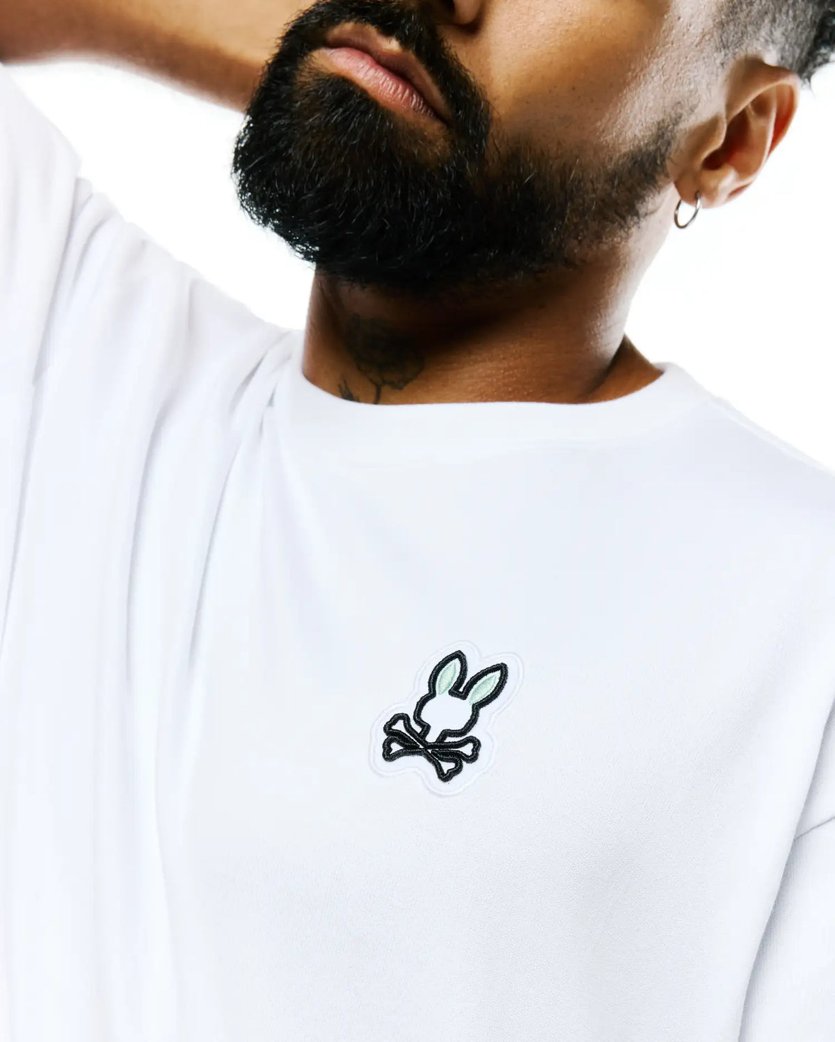 Mens Jaydon Pima Cotton Oversized-Fit Tee in crisp white, featuring a smooth jersey texture and a prominent embroidered Psycho Bunny skull logo with black outline and light green ears on the left chest. (2)