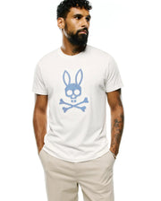 Mens Stan Pima Cotton Graphic Tee, a classic fit cream jersey t-shirt featuring a large blue checkered Psycho Bunny skull and crossbones graphic on the chest. (1)