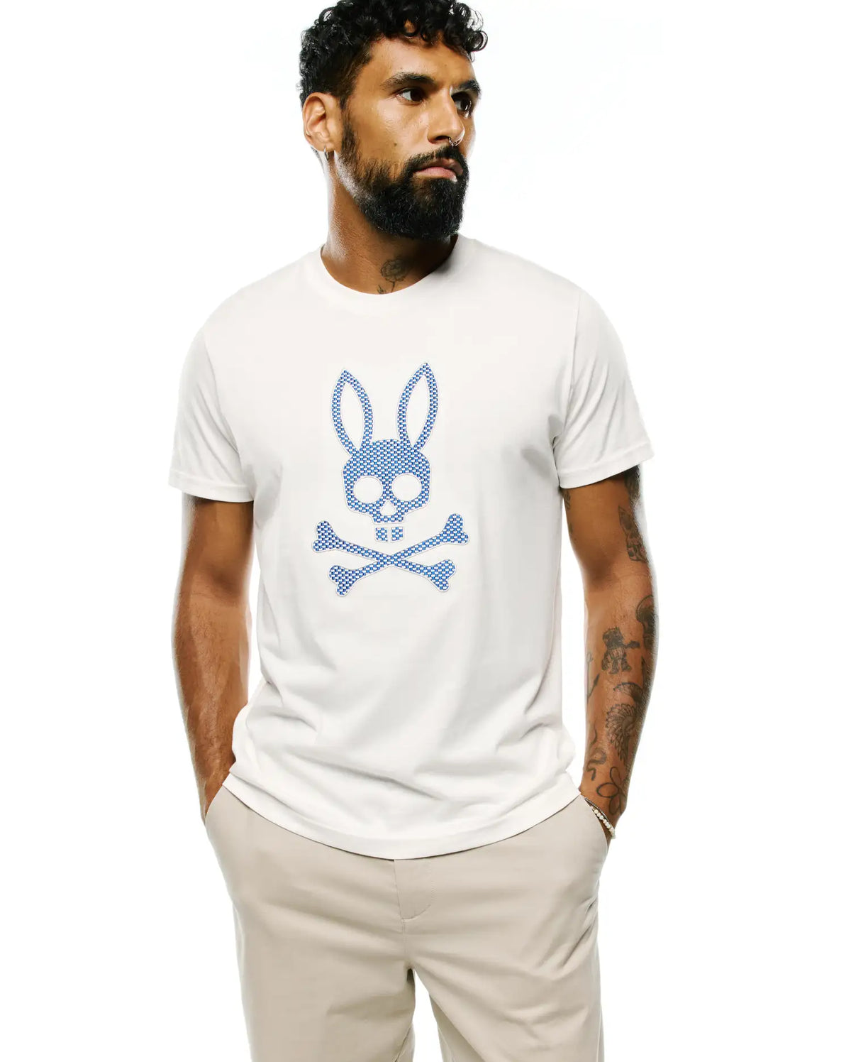 Mens Stan Pima Cotton Graphic Tee, a classic fit cream jersey t-shirt featuring a large blue checkered Psycho Bunny skull and crossbones graphic on the chest. (1)