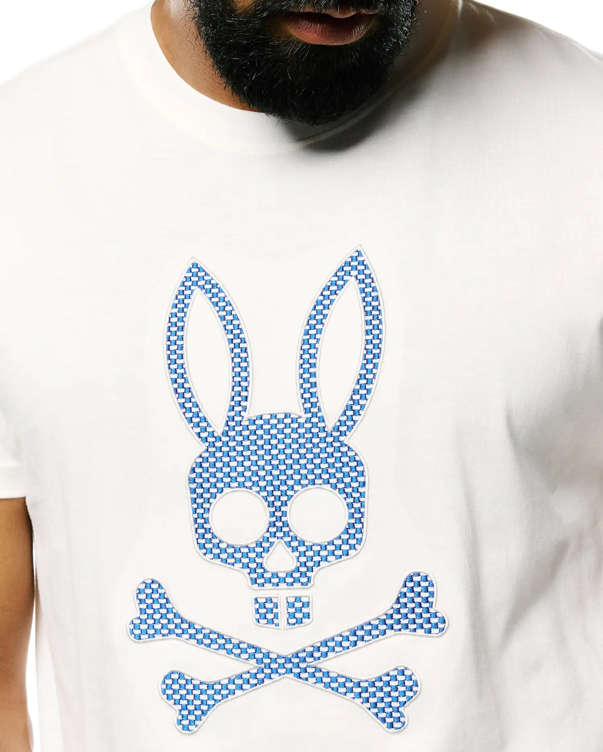 Mens Stan Pima Cotton Graphic Tee, a classic fit white Pima cotton jersey t-shirt with a large central embroidered Psycho Bunny skull and crossbones logo featuring a blue and white checkered pattern. (2)