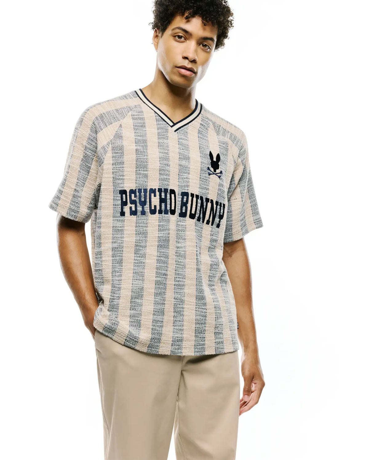 Mens Nathaniel Relaxed Raglan Tee in beige and blue vertical stripe textured knit, featuring a navy V-neck, embroidered Psycho Bunny skull logo, and large PSYCHO BUNNY text across the chest. (3)