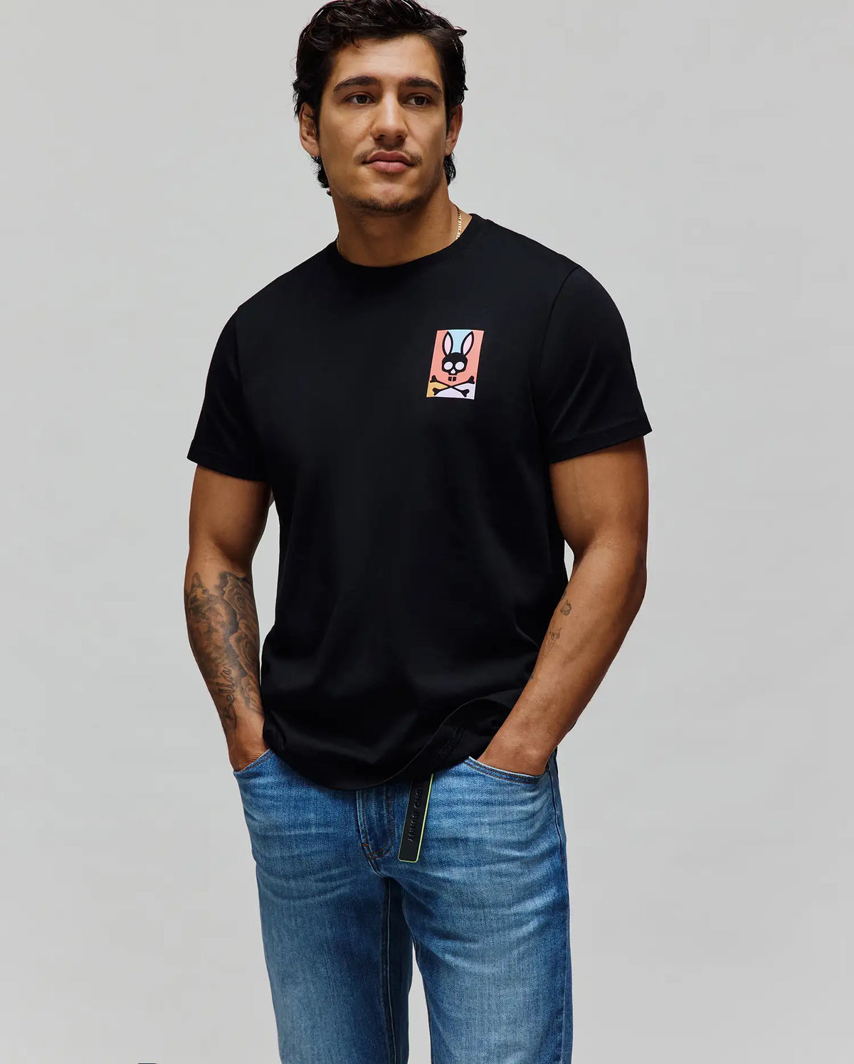 Black Mens Raphael Back Graphic Tee, a classic fit jersey t-shirt featuring a small, colorful gradient Psycho Bunny skull logo graphic on the left chest.