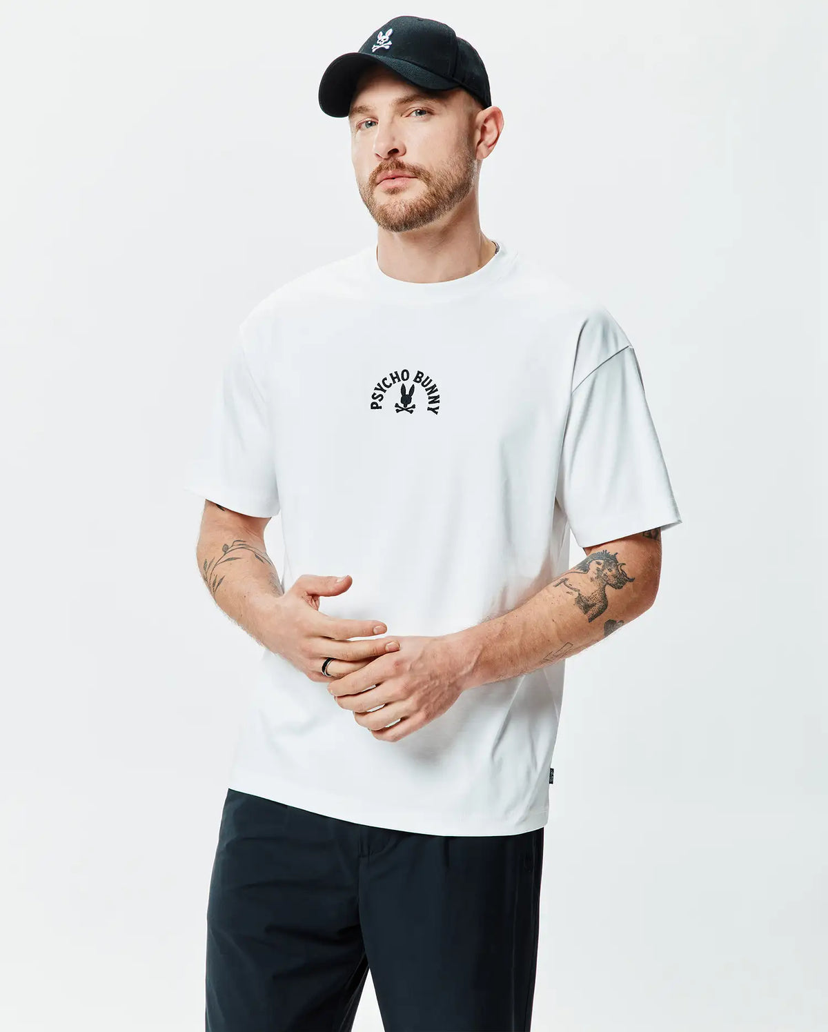 Mens Stevie Relaxed Fit Tee, a white smooth jersey t-shirt featuring a black arched PSYCHO BUNNY text and iconic bunny skull logo centered on the chest. (1)