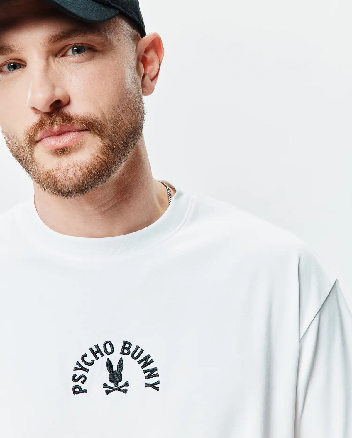 Mens Stevie Relaxed Fit Tee, premium white jersey knit, featuring a prominent black embroidered Psycho Bunny skull logo with arched text on the center chest. (2)