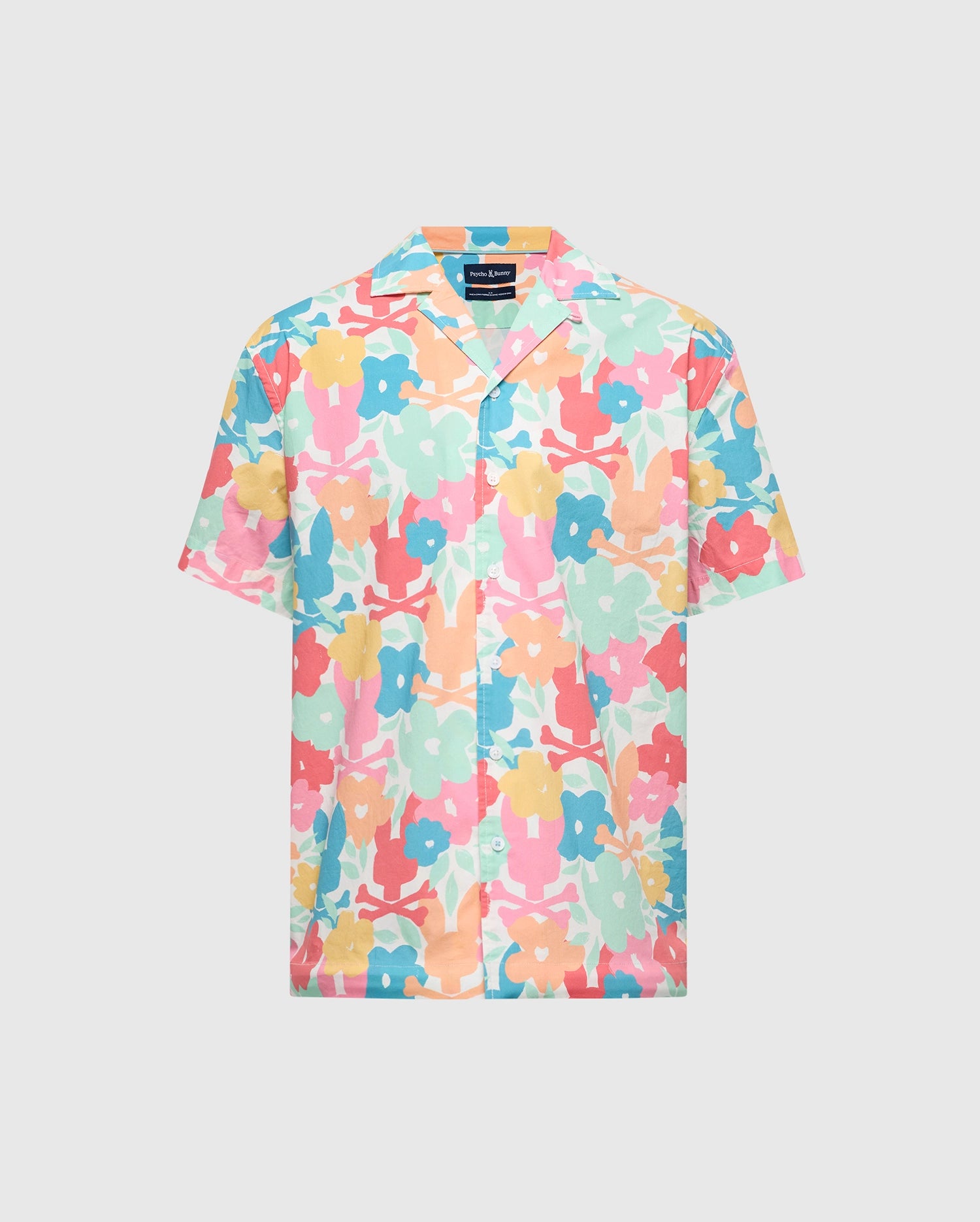 The Psycho Bunny MENS MEYLON STRETCH POPLIN SHIRT (MT0300034) is a short-sleeved shirt with a camp collar, featuring a vibrant floral pattern of large pink, blue, yellow, and green flowers on a light background. It offers a relaxed fit and includes an embroidered logo for extra flair.