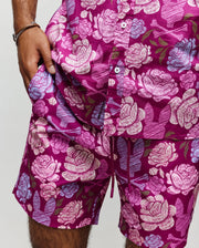 Wearing Psycho Bunny’s MENS ROWEN SHIRT - MT0300038, a person in matching magenta shorts is shown with one hand in their pocket, displaying only their lower torso and upper legs.