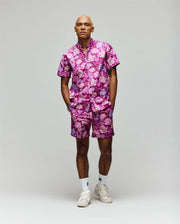 A person stands facing forward in the Psycho Bunny MENS ROWEN SHIRT - MT0300038, paired with white socks and sneakers, against a plain light gray background.