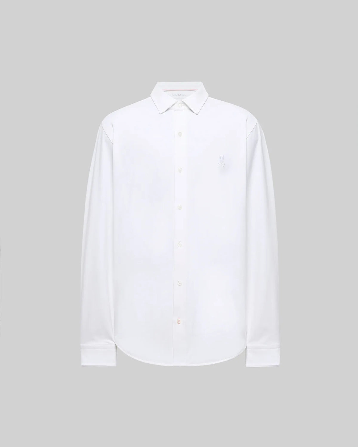 The Psycho Bunny MENS JIM JERSEY KNIT SHIRT (MT0300067) is a long-sleeved, white, athletic-fit shirt with a collar and a subtle embroidered logo on the upper left chest, shown on a plain light gray background.