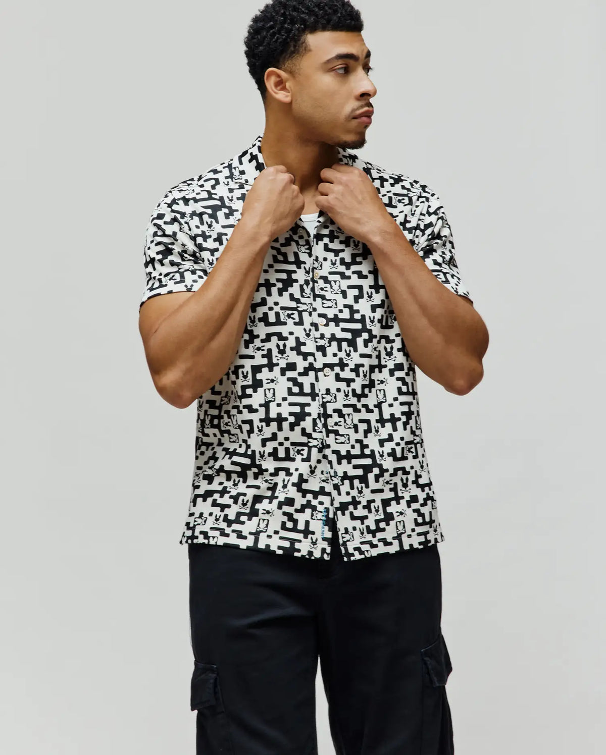 Mens Josh Jacquard Shirt, classic fit, white with an all-over black pixelated geometric pattern featuring small Psycho Bunny skull logos, and a blue Psycho Bunny tag on the left hem.