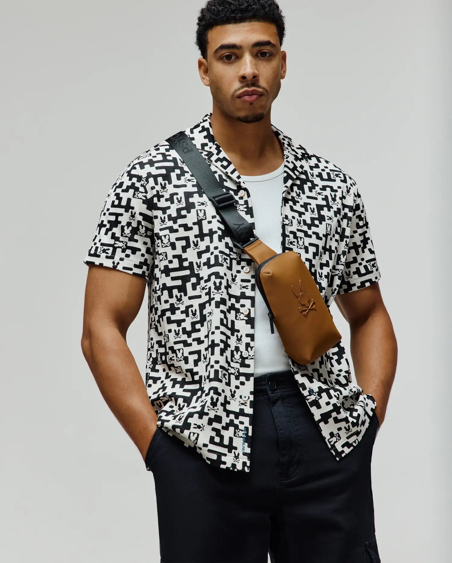 Mens Josh Jacquard Shirt, a relaxed fit short-sleeve button-up in white with an intricate all-over black geometric and pixelated Psycho Bunny skull logo pattern, crafted from a soft woven fabric.