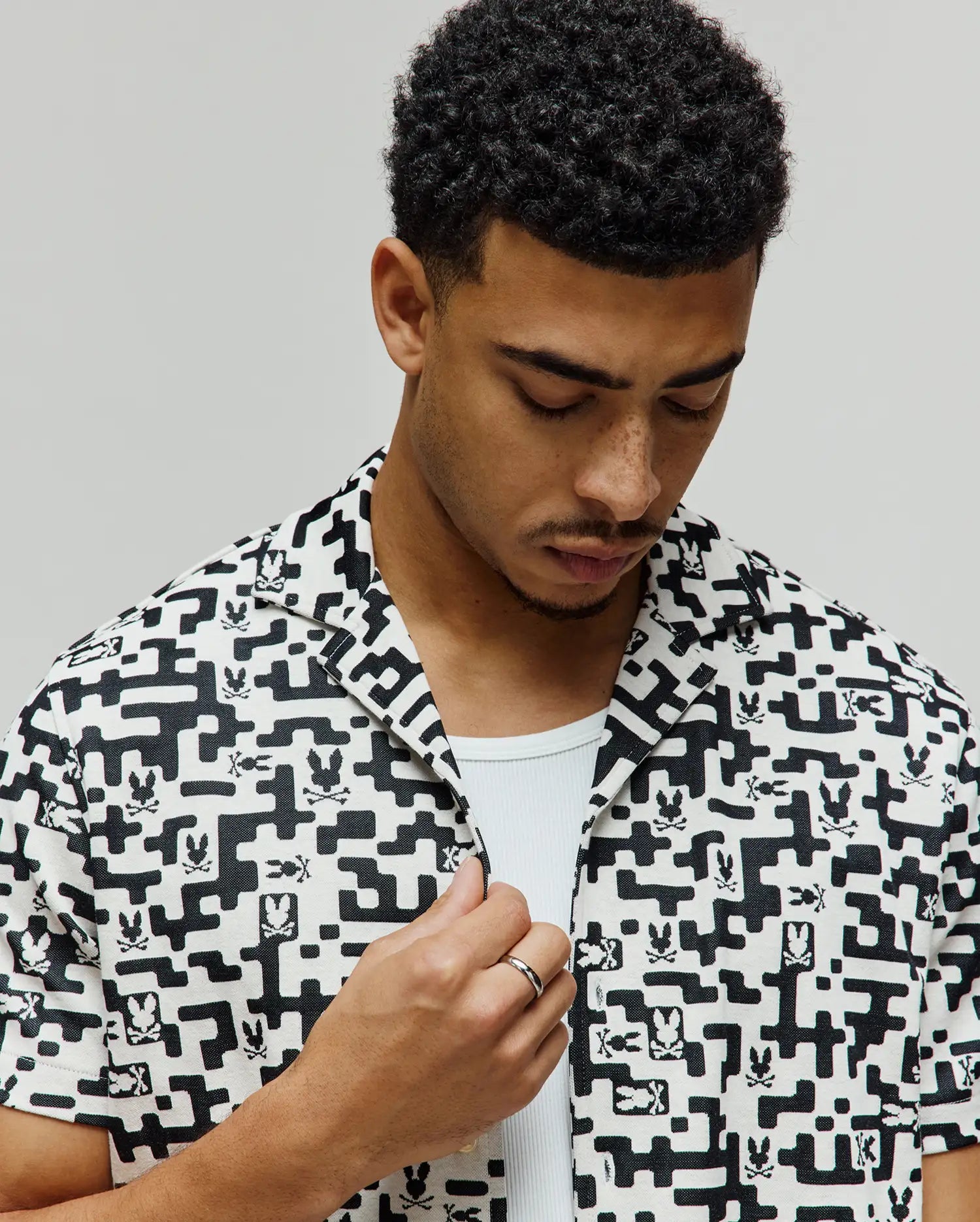 Mens Josh Jacquard Shirt, a black and white all-over pixelated geometric pattern with integrated small Psycho Bunny skull logos, featuring a relaxed fit and short sleeves.
