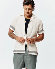 Mens Sunny Linen Shirt, off-white, relaxed fit, with a textured linen fabric, featuring black zigzag patterns on short sleeves and hem, plus a small embroidered Psycho Bunny skull logo on the left chest. (1)