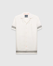 Mens Sunny Linen Shirt, an off-white relaxed linen camp collar shirt, features black zigzag patterns on sleeves and hem, an embroidered Psycho Bunny logo left chest, and orange collar trim. (5)