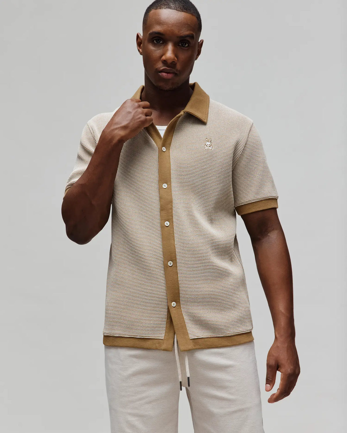 Mens Maxton Waffle Shirt, a classic fit short-sleeve button-down in beige and brown waffle knit, featuring a solid brown collar, placket, cuffs, hem, and a small embroidered Psycho Bunny skull logo on the left chest.