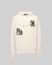 The Psycho Bunny MENS AUGUSTE HOODIE - MT0500043 is a cream-colored premium cotton hoodie with a front pocket, chenille floral detailing, an embroidered “PB” and flower patch on the left chest, plus a black bunny and flower patch on the right.