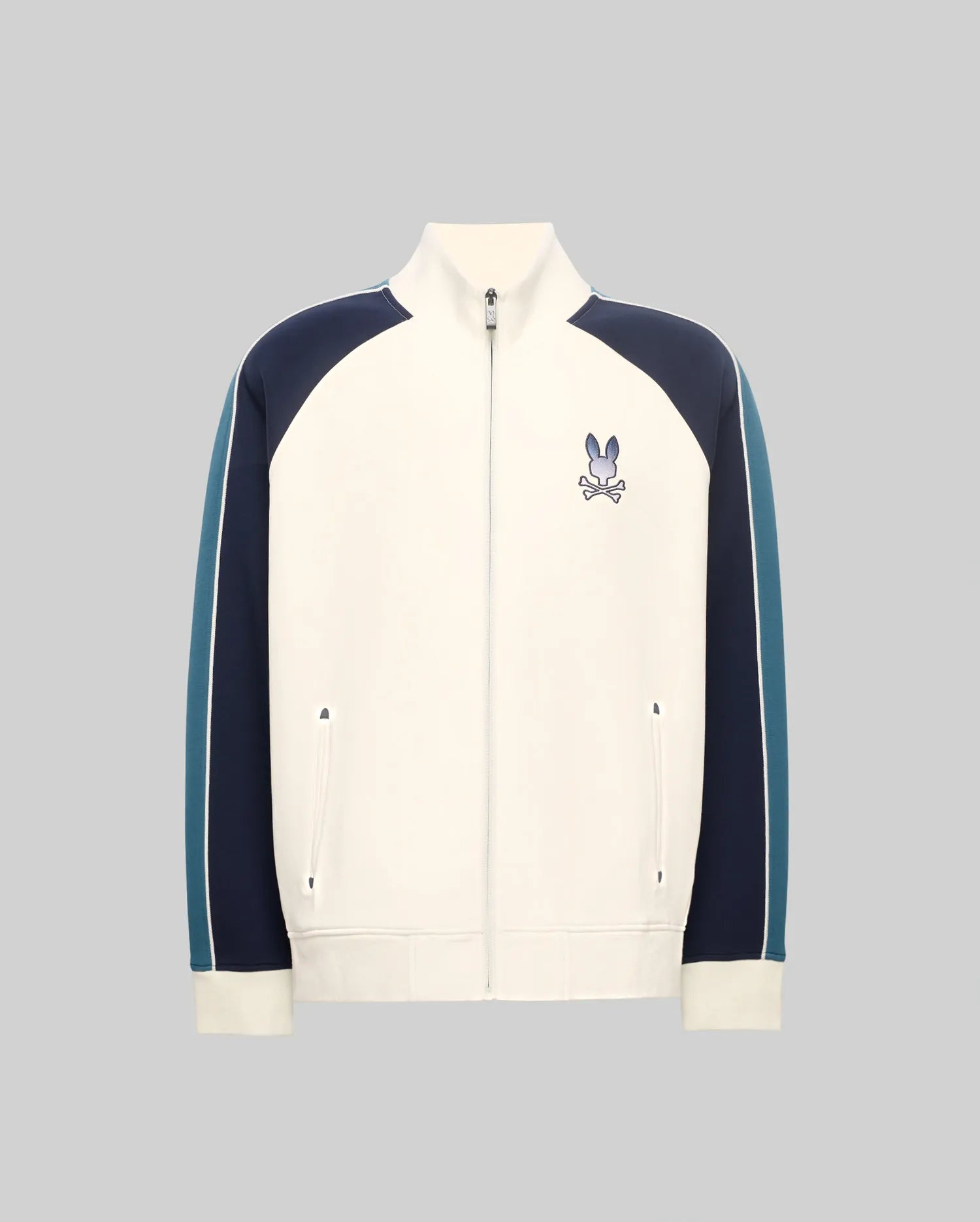 Cream classic fit Mens Caspian Track Bomber with navy and teal color block raglan sleeves, white stripe detail, ribbed cuffs/hem, and embroidered Psycho Bunny skull logo on left chest.