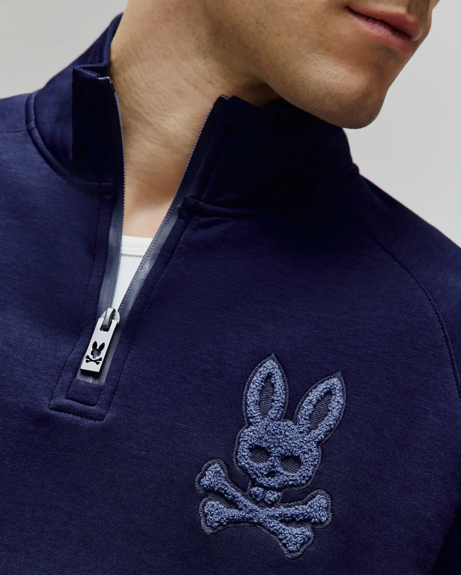 Mens Tate 1/4 Zip Chenille Pullover in deep navy, featuring a stand-up collar, silver Psycho Bunny logo zipper pull, and a large, textured chenille bunny skull logo on the left chest.