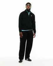 Men's Samson Quarter-Zip Sweater, a classic fit black smooth knit quarter-zip with a collared neckline, light blue accent at the collar and hem, and a small embroidered white Psycho Bunny skull logo on the left chest. (1)