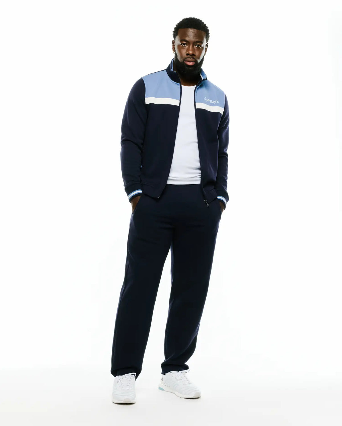 Men's Jacques Pique Track Jacket in navy, featuring a classic fit, light blue and white color-block chest panels, a white embroidered Psycho Bunny script logo on the left chest, and striped ribbed cuffs. (2)