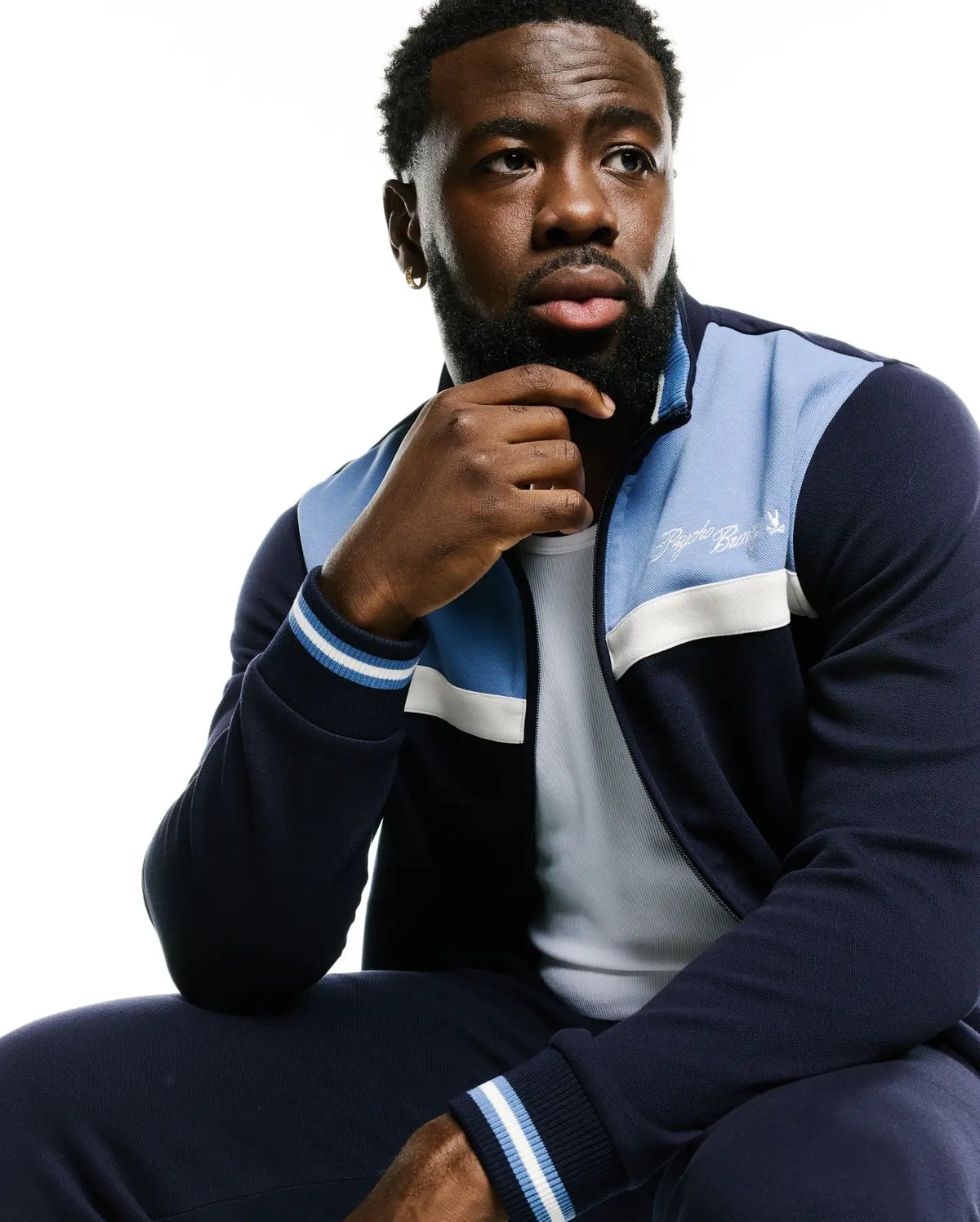 Men's Jacques Pique Track Jacket in navy with light blue and white color-blocked panels, featuring a full zip, ribbed cuffs with stripes, and an embroidered white Psycho Bunny script logo on the left chest. (5)