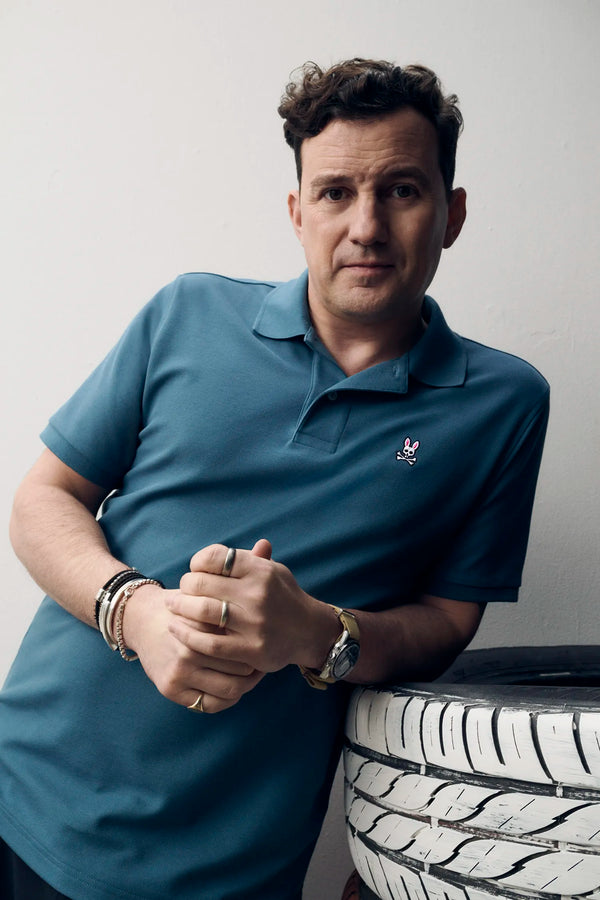 Mens Classic Pique Polo in teal blue, featuring a classic fit and visible pique knit texture. Small embroidered pink, white, and black Psycho Bunny skull logo on the left chest.