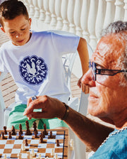 White Kids Toby Graphic Tee, classic fit, soft jersey, featuring a large central blue Psycho Bunny skull and NYC text graphic, paired with mint green relaxed shorts.