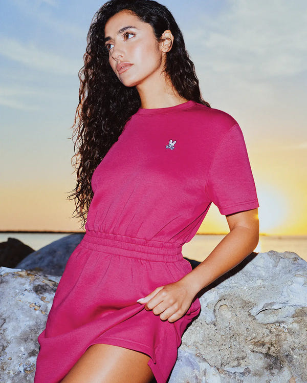 Womens Penelope Dress in vibrant magenta jersey knit, featuring a relaxed fit, elasticated waist, and a small embroidered Psycho Bunny skull logo on the left chest.
