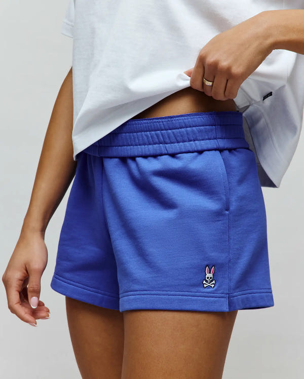 Womens Olivia Fleece Short, vibrant blue, relaxed fit, soft fleece with elastic waistband and side pockets, featuring a small embroidered Psycho Bunny skull logo with pink ears on the lower left leg.