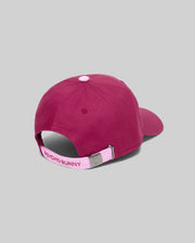 Womens Amaris Baseball Cap in deep magenta cotton twill, featuring a light pink top button and adjustable back strap with embroidered Psycho Bunny text and a silver metal buckle debossed with the iconic bunny skull logo.