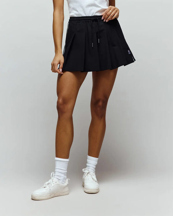 Womens Cecilia Sport Skort, black pleated design with white side stripes, drawstring waist, and a small embroidered purple Psycho Bunny skull logo on the lower right.