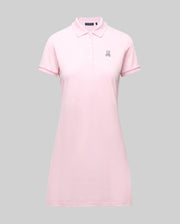 The Psycho Bunny WOMENS POLO DRESS - WO2000003 is a light pink Pima polo dress featuring a feminine silhouette, short sleeves, collar, Mother-of-Pearl buttons, and an embroidered white bunny logo on the left chest, shown on a gray background.