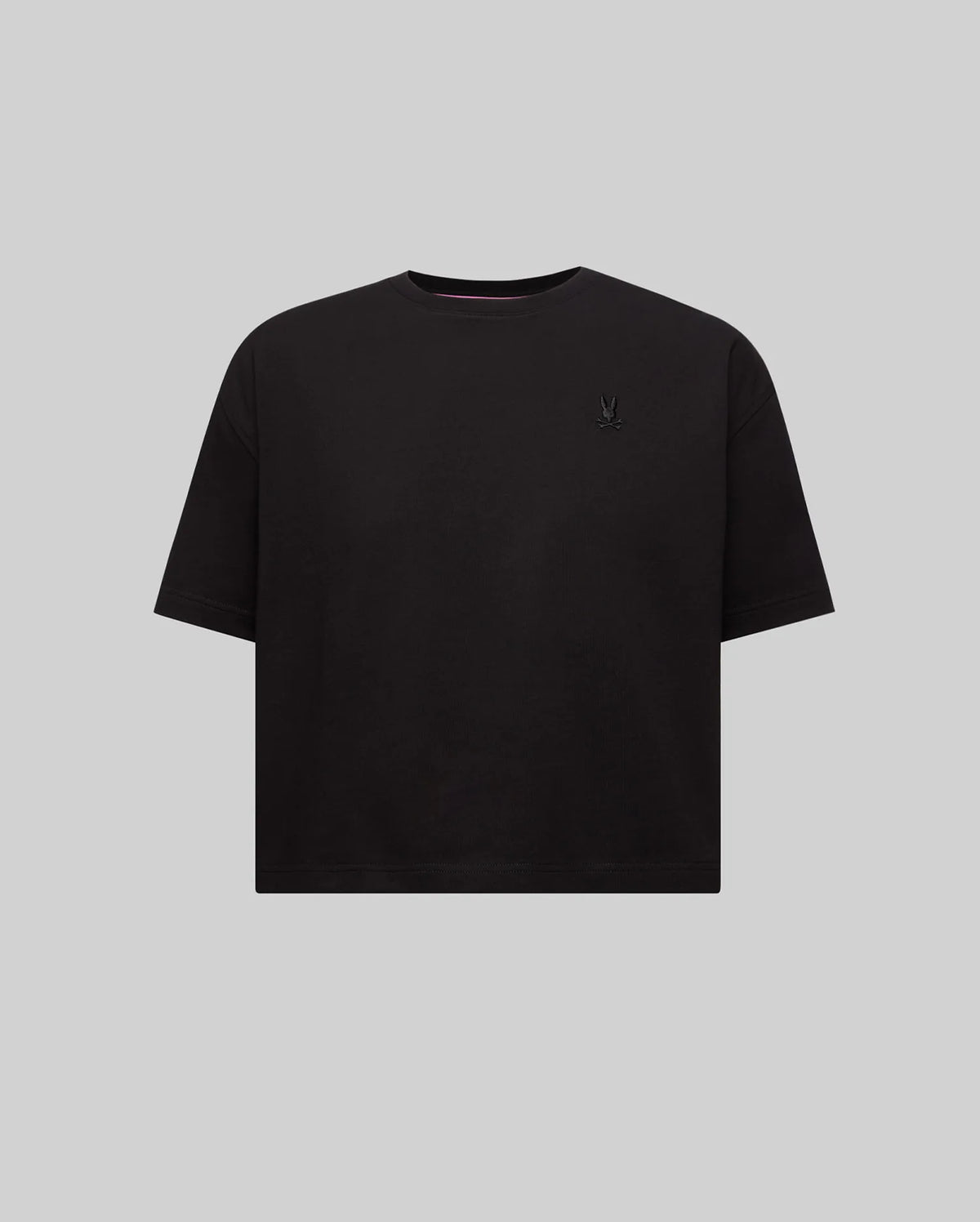 Women's Camille Oversized Fit Tee, a black oversized jersey knit t-shirt featuring a small embroidered black Psycho Bunny skull logo on the left chest and pink neck tape.