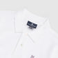 Close-up of a white Psycho Bunny Pima cotton Mens Classic Polo - B6K001ARPC showcasing the crease-resistant collar with a visible brand tag and a small embroidered bunny logo on the chest.