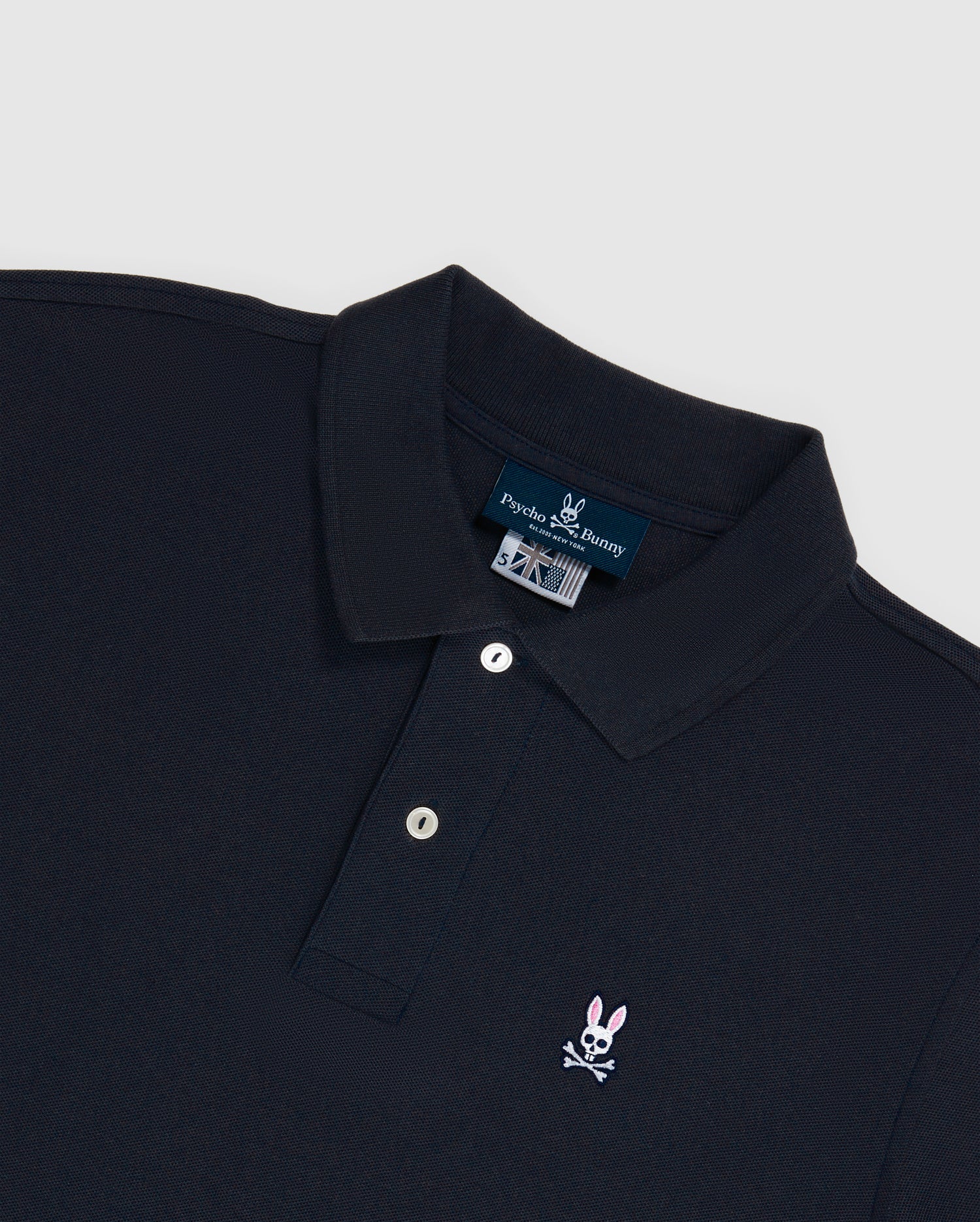 The Psycho Bunny Men's Big and Tall Classic Piqué Polo Shirt (B9K001ARPC) is made from soft Pima cotton and features a collar, buttoned placket, and black diamond-knit piqué fabric with a small pink bunny embroidered logo with a skull on the left chest.